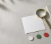 A blank card, a magnifying glass and three blank circular markers arranged on a light surface, illustrating a product-label check