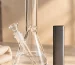 A plain unbranded water pipe and a slim rectangular device side by side on a pale stone surface with a folded cloth
